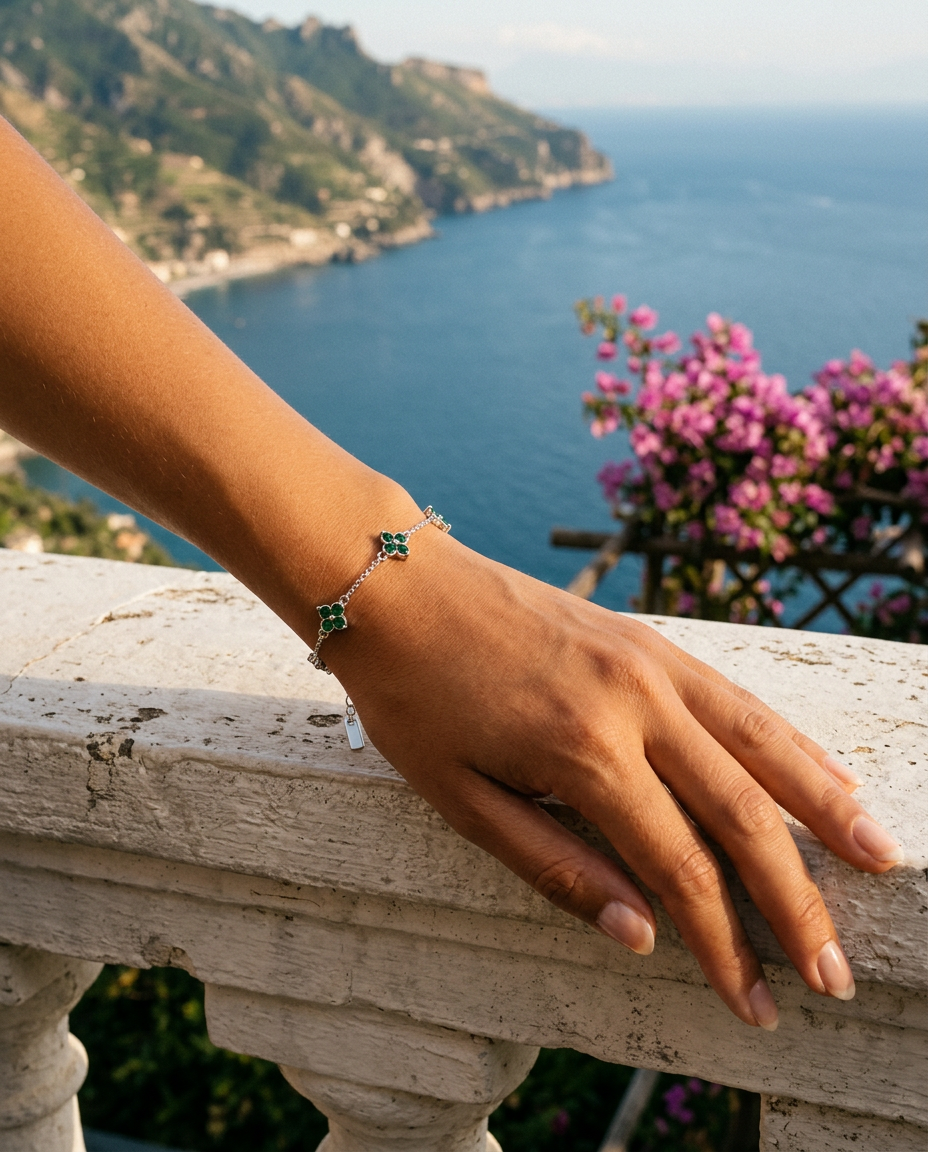 Polso con The Fortuna Bracelet su una balaustra in pietra con bouganville e mare