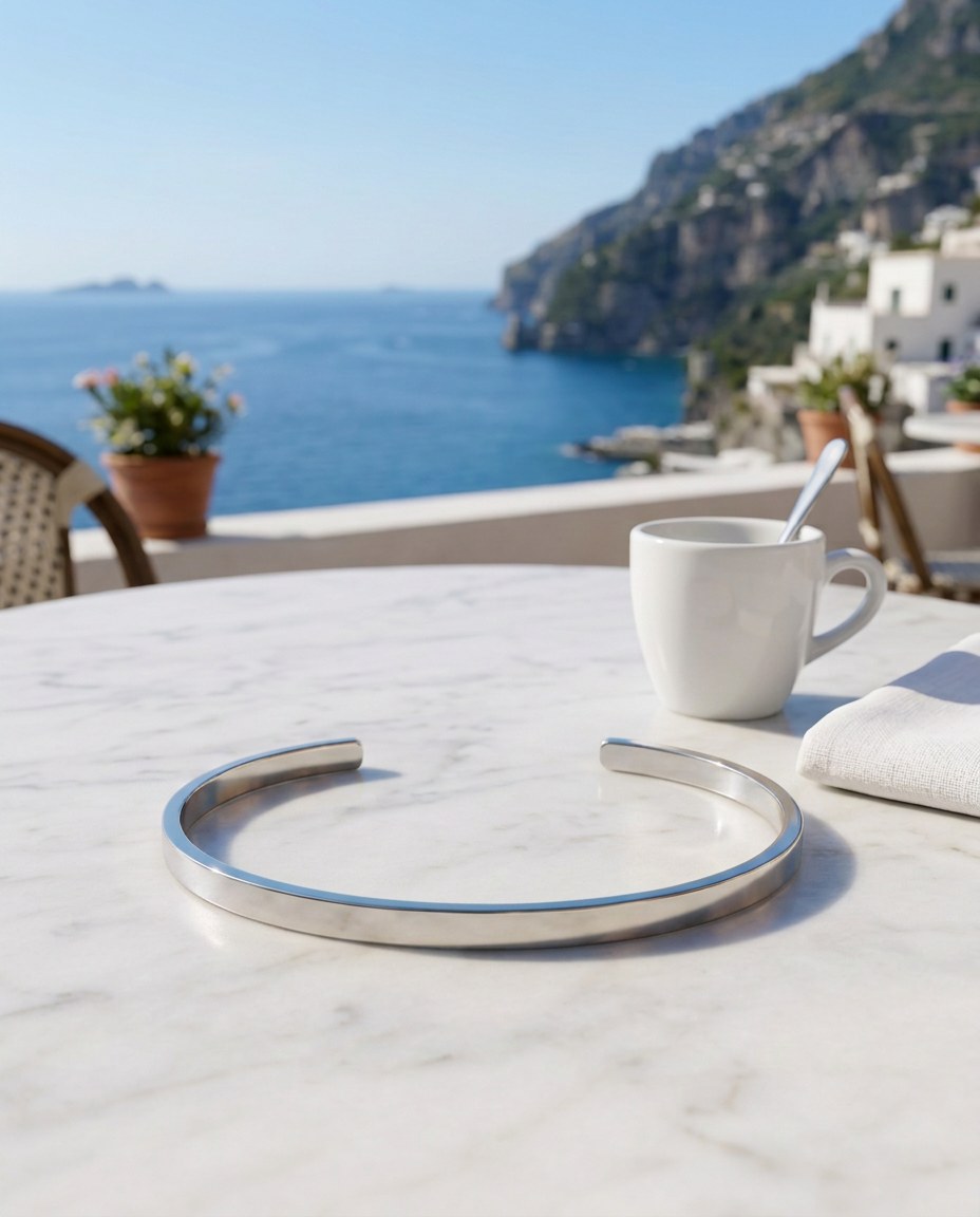 The Capri Slim Flat Bracelet auf einem Marmortisch mit Espresso und dem Meer von Capri