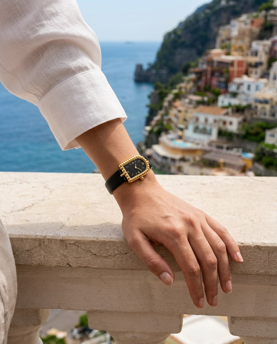 The Amalfi Black/Gold en la muñeca de una mujer con lino blanco en la Costa Amalfitana